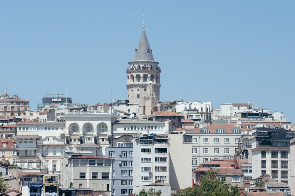 A daytime view of the iconic Galata Tower surrounded by Istanbul's urban landscape